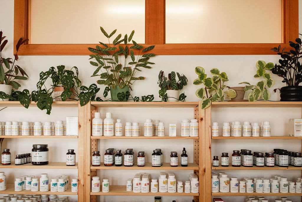 Wooden shelves of herbal supplements topped with houseplants