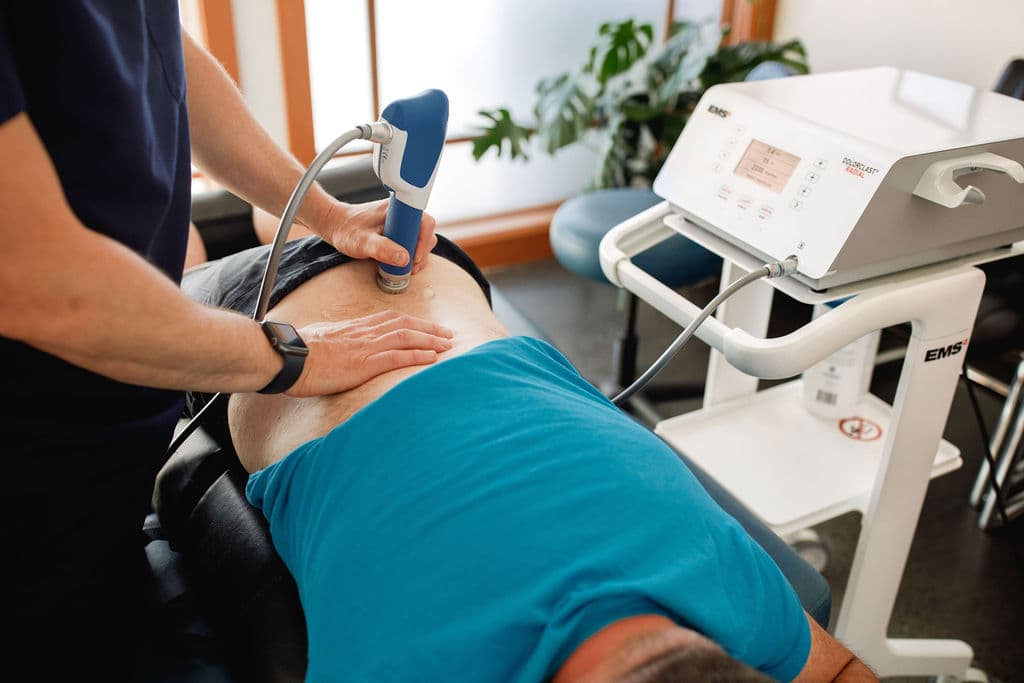 Dr. Borys applying the EMS Dolorclast Radial shockwave handpiece to a patient's lower back