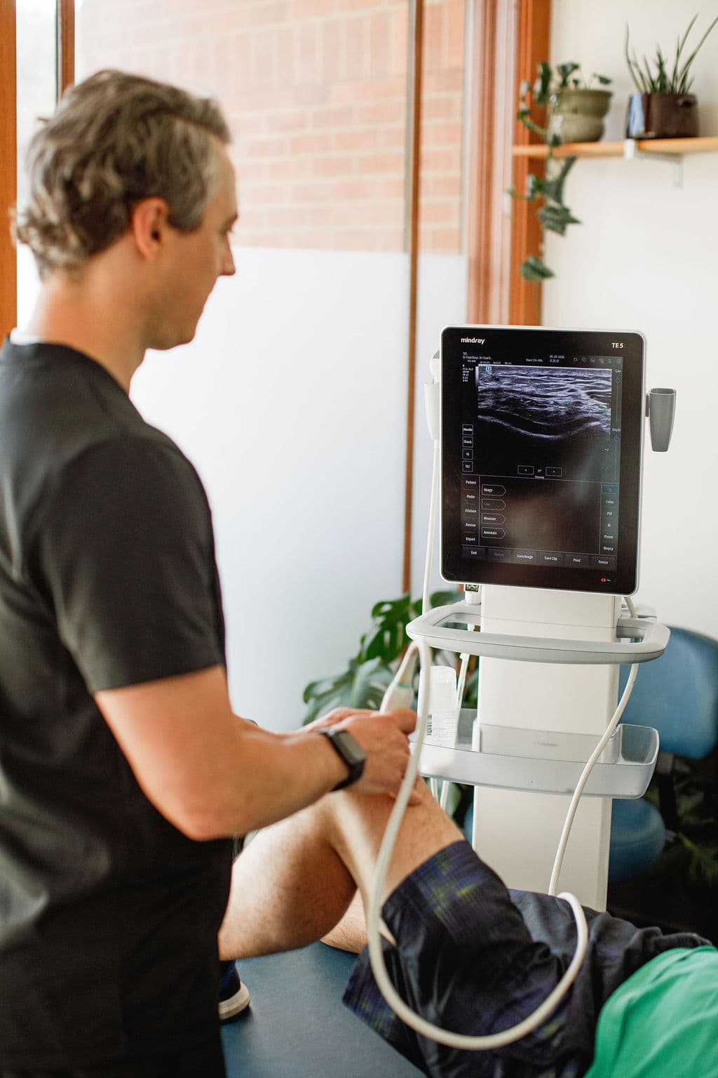 Dr. Borys reviewing an ultrasound scan beside the Mindray machine during a treatment session